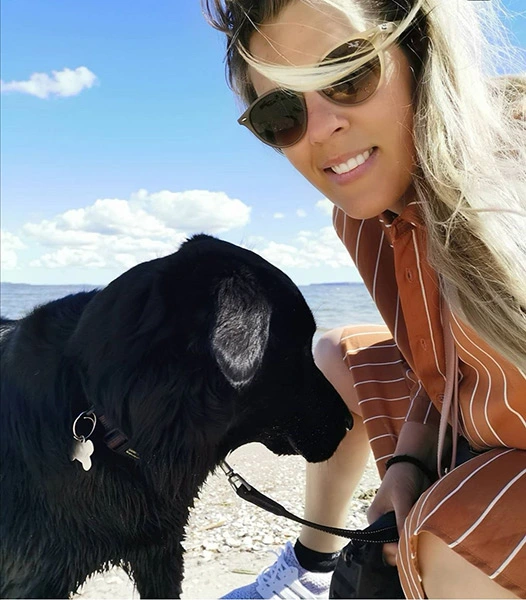 Kvinde og sort hund på strand